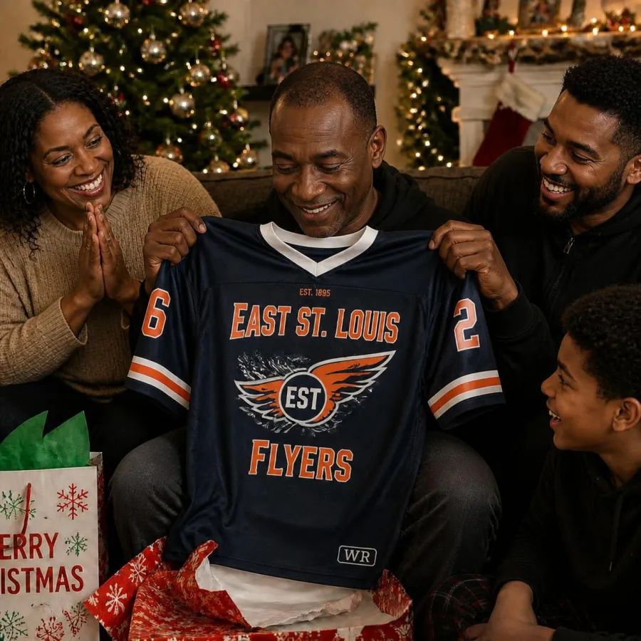 A father smiles as he holds up the custom East St. Louis Flyers jersey his family gave him for Christmas